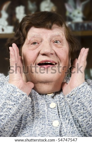 Portrait of grandma making a surprised face and  holding hands near face