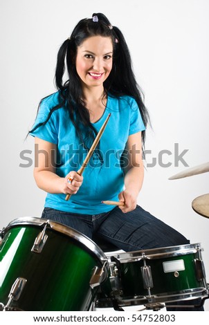 Beauty drummer with pigtails smiling and playing drum set with drumsticks
