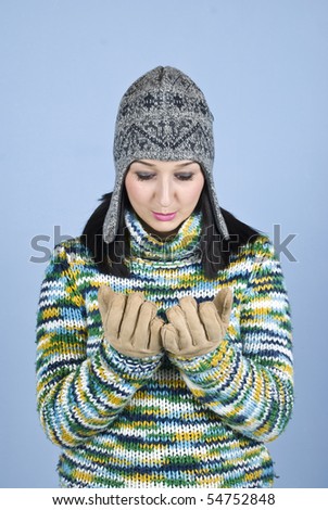 Youth female in winter gloves looking in empty hands with gloves and have nothing and she is disappointed over blue background