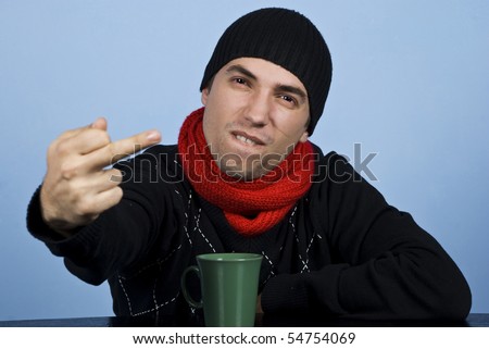 Young man in winter clothes being very upset and showing obscene gesture