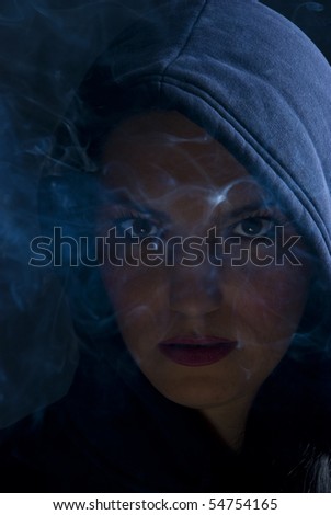 Bad woman hooded in darkness with smoke
