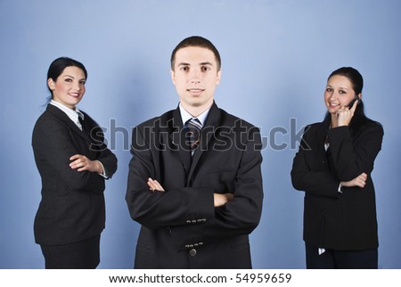 Business man leader in front of image and his colleagues in background,a business woman speaking by cell phone and the other standing with hands crossed and smiling