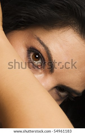 Beautiful woman  standing with head inclined,hidden her face with hand  and looking  with big eyes to side,at camera