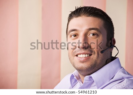 Portrait of young man operator support smiling  and looking you,vertical blinds background,copy space for text in left part of image