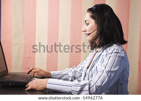 Support operator mid adult woman typing at laptop in office,vertical blinds background