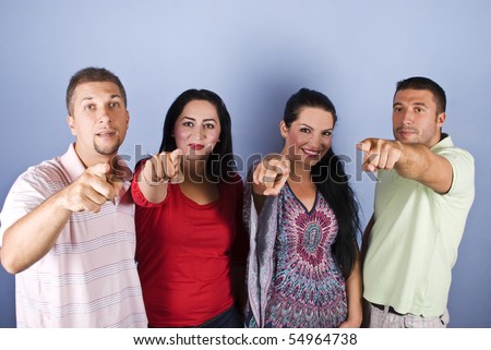 Portrait group of happy people pointing in all directions like  they choice something or someone on blue background
