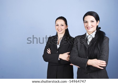 Two business women standing one close to each other with hands crossed and smiling for you,copy space for text message in left part of image