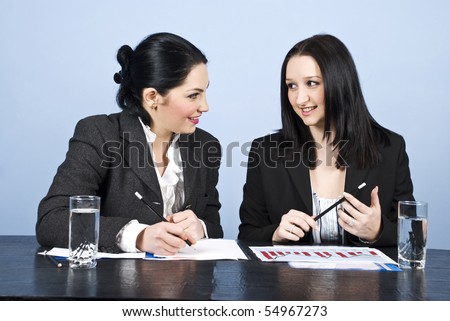 Two young business women having a n conversation at meeting