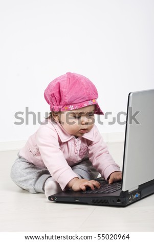 Concentrated baby girl sitting on floor and typing on laptop ,copy space for text message