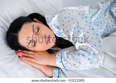Beautiful woman sleeping with hands under face in her bed