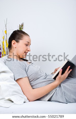 Cheerful woman read a book and sitting comfortable on bed