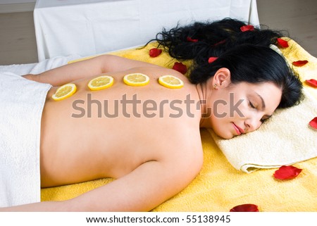 Beautiful woman lying  at spa massage  and having a therapy with lemon  slices on her back