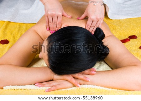 Brunette woman at spa salon getting a shoulders  massage from a professional masseuse