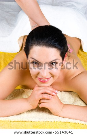 Smiling brunette woman enjoying a back massage at spa and sitting with hands under chin