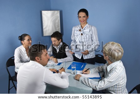 Business woman making a speech and holding a paper at meeting with her colleagues