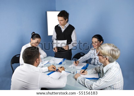 Meeting of business people in a office ,a young businessman standing with a blank paper in his hands and say a speech