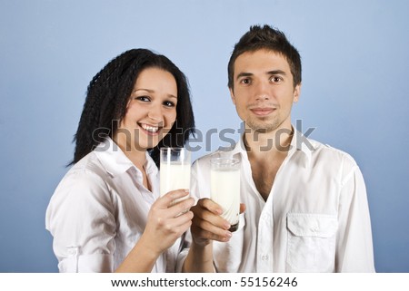 Youth happy couple holding glasses with milk and smiling,they wear white clothes on blue background