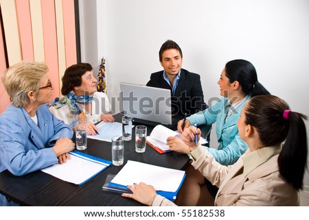 Young and senior people having a business meeting in an office and sitting around table making conversation  and laughing