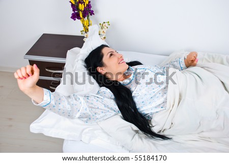 Smiling young woman stretching her hands in bed and wake uo