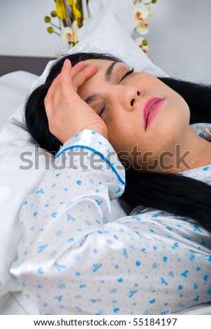 Close up of woman having headache and lying on bed with hand on head