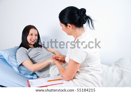 Friendly doctor woman holding  her pregnant patient hands and talking with her