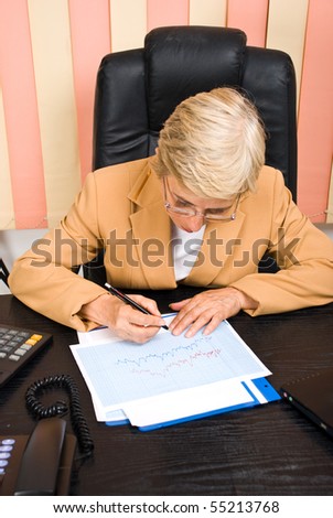 Executive senior woman financial analyst  writing on graphs