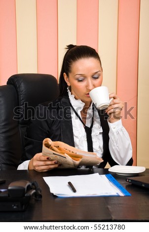 Young business woman drinking coffee and read the news in newspaper  at office in the morning