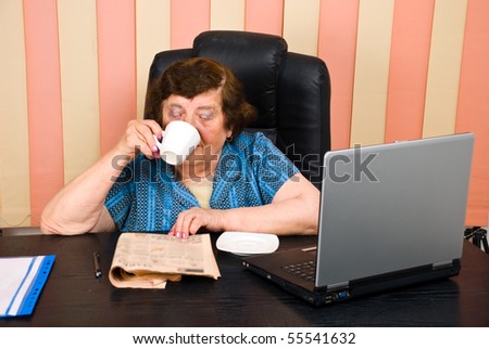 Elder executive woman reading news and drinking coffee at office