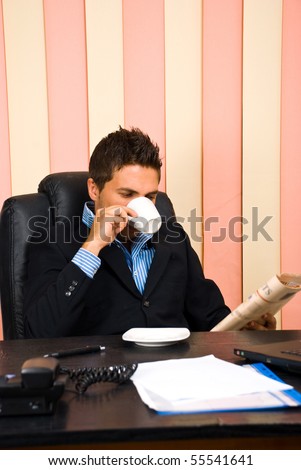 Corporate man reading news and drinking coffee at office