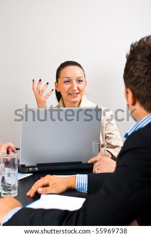 Business woman using laptop and explaining something to a man  at a meeting,she gesticulate with hand and laughing