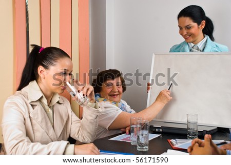 Laughing elderly woman indicate with pencil on blank board and all business people having fun at meeting