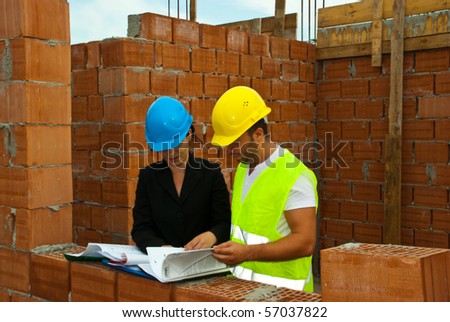 Two architects having a discussion and reading folders or looking on projects in a house under construction outdoor