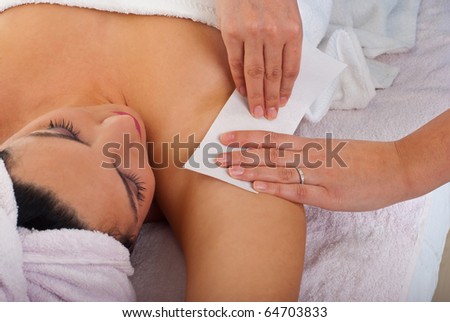 Beautician waxing armpit to a woman in a salon
