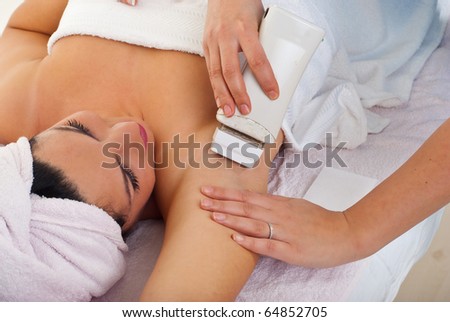 Beautician waxing woman\'s armpit at spa salon
