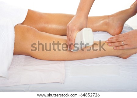 Beautician waxing woman\'s leg at spa salon