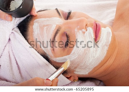 Close up of hand applying facial mask to woman face at  beauty salon