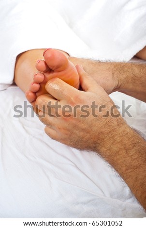 Health worker giving reflexology massage to woman feet