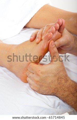 Detail of man hands doing reflexology massage to woman feet
