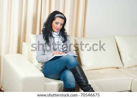 Business woman sitting on couch  home and writing in agenda
