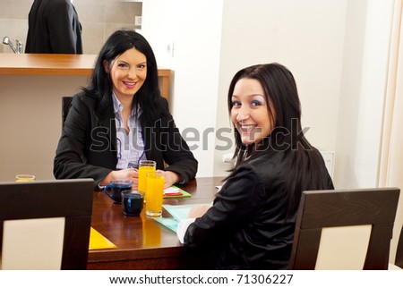 Two happy business women sitting on chair at  meeting table