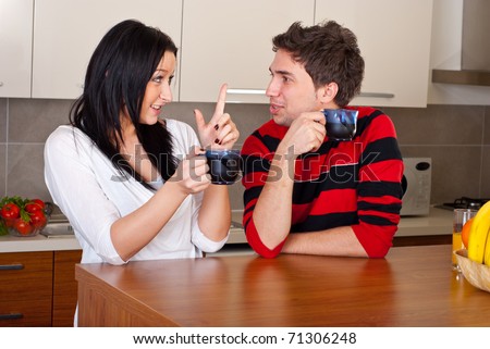 Young couple drinking coffee in the morning and having conversation in their kitchen