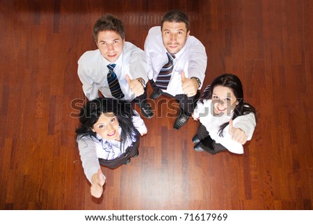 Top view of four business people giving thumbs and looking up