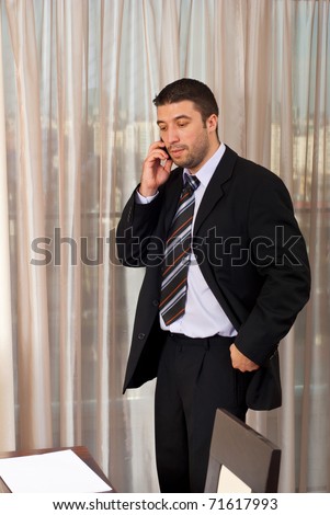 Worried business man talking on phone mobile in office and looking down