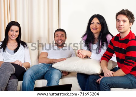 Happy four friends having a meeting in a house and sitting together on couch