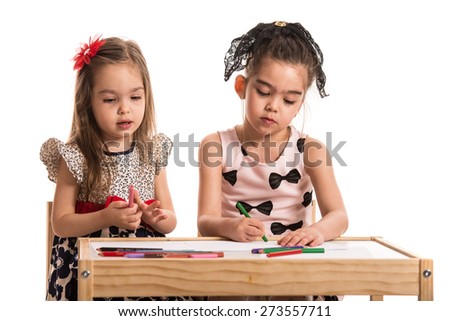 Two girls at kindergarten drawing with colored sketch pens on papers