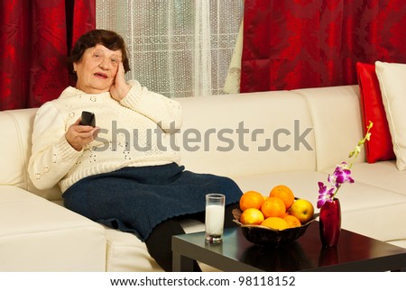 Single  surprised elderly woman watching tv in her living room