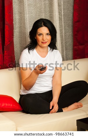 Woman sitting on couch with legs crossed and watch tv