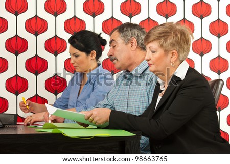 Three business people sitting at meeting table and working togheter in office