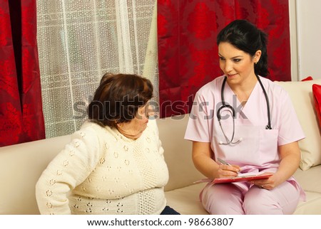 Doctor woman talking with elderly woman and writing clipboard  in her home