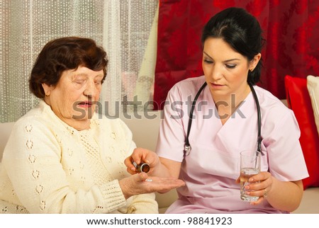 Doctor gives pills and water to senior woman patient in her home